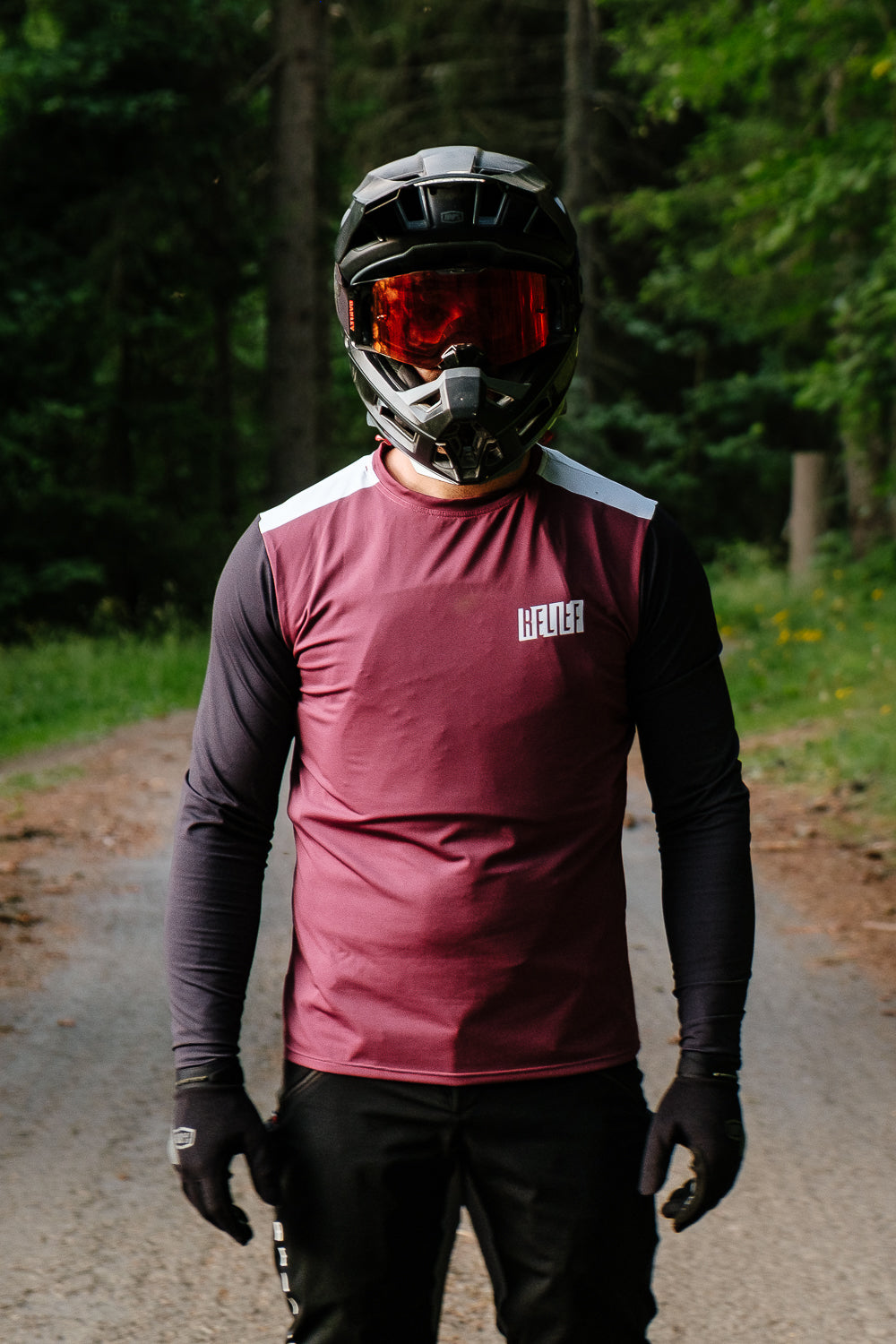 Maillot VTT homme rouge grenat RELIEF Équipements Maillot VTT homme rouge grenat RELIEF Équipements qui pose dans la forêt